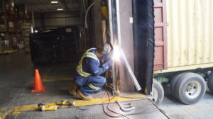Technician welding track on overhead dock door