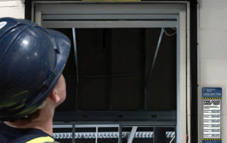 Fire door drop test inspection with technician multi-point checklist on phone and sticker tracker