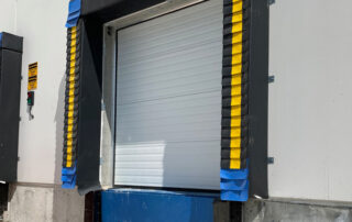 Blue Giant hydraulic elevating dock leveler plate, steel face dock bumper, electric hook trailer vehicle restraint HVR303, stationary dock seal 101, steel sectional overhead vertical lift door